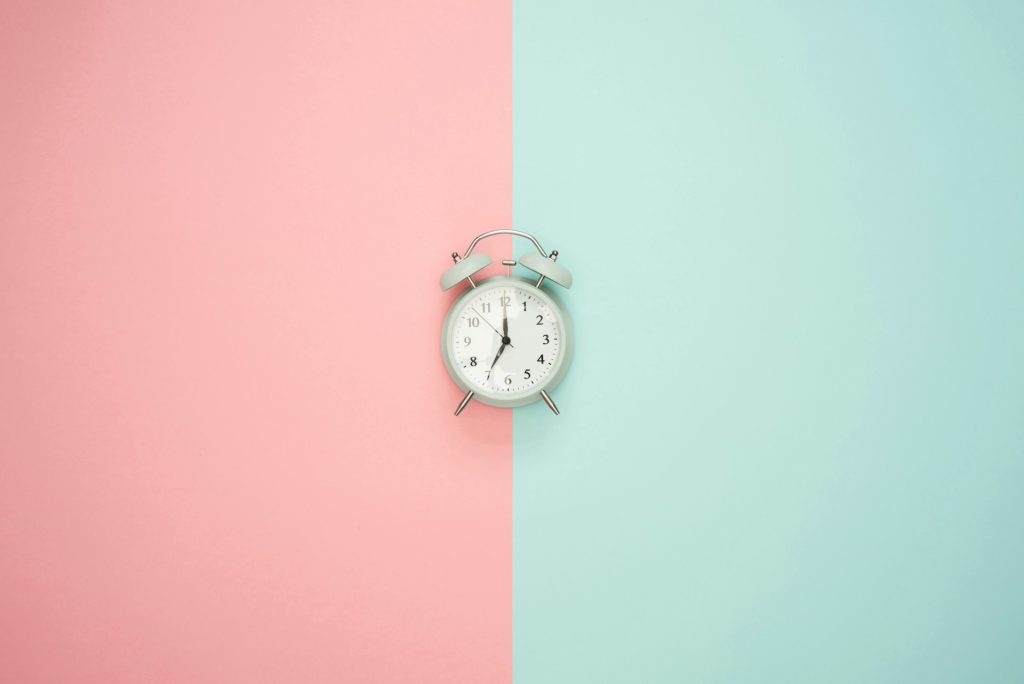 Photo of a clock overlayed on a half-pink, half-teal background