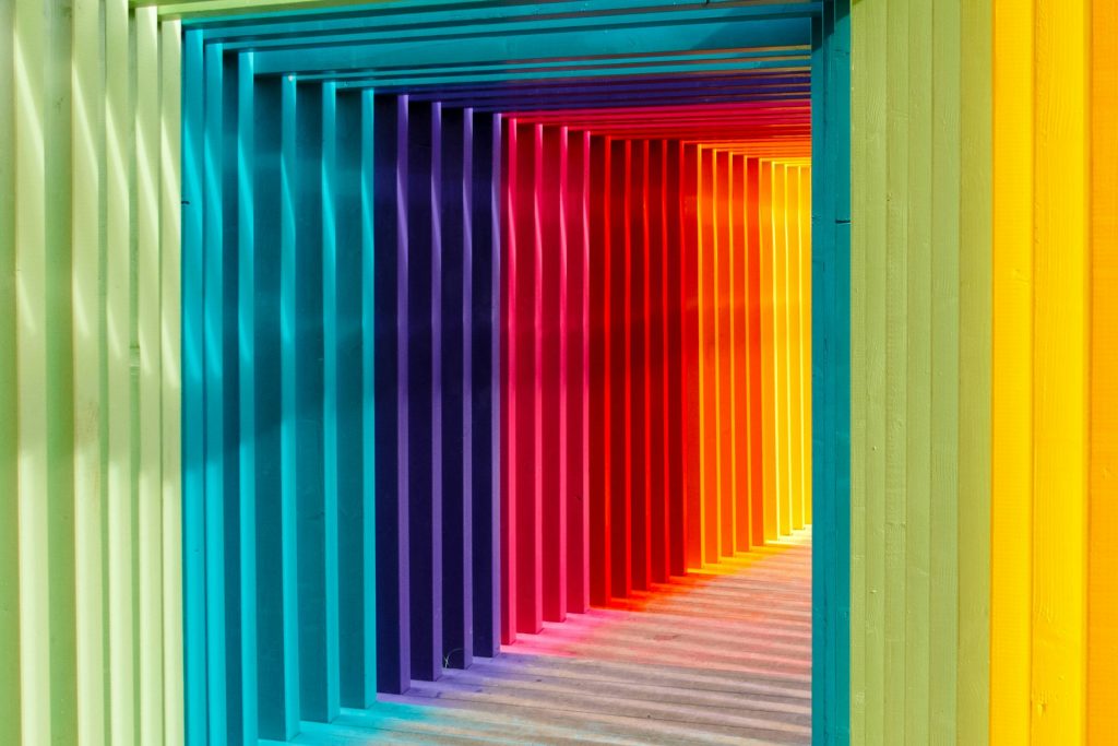 Photo of a hallway lined with multicolored beams arranged in a rainbow pattern